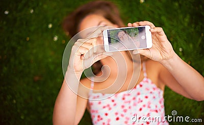 Taking a summer selfie to share with her friends. a young woman taking a selfie while lying on the grass. Stock Photo