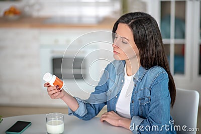 Black-haired womn looking at the pills container Stock Photo