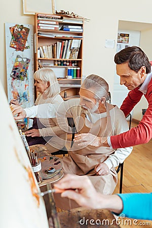 Talented artist helping elderly man in painting studio Stock Photo