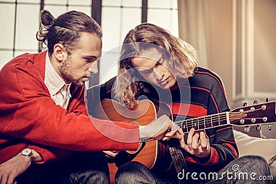 Bearded guitar tutor feeling busy teaching his talented student Stock Photo