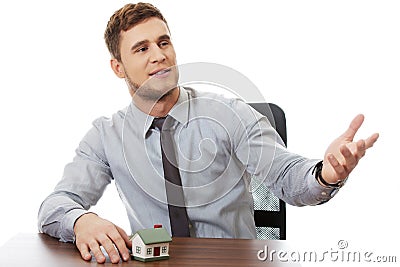 Talking businessman with house model by a desk. Stock Photo