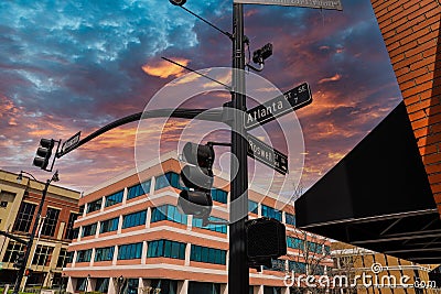 A tall black pole with street signs that read `Atlanta` and `Roswell` and traffic signals surrounded by office buildings Stock Photo