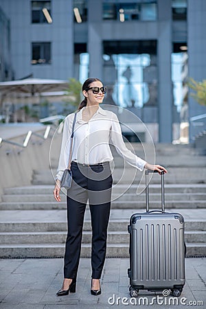 Tall brunette woman standing near her big suitcase Stock Photo