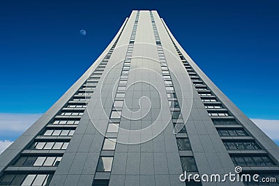 A tall building that goes into sunset sky and rainy clouds the sky. Stock Photo