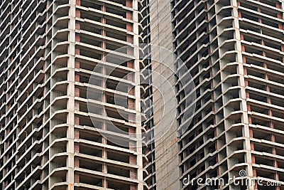 Tall concrete structures rise in an urban setting, showcasing incomplete frameworks and open spaces. Workers are active Stock Photo