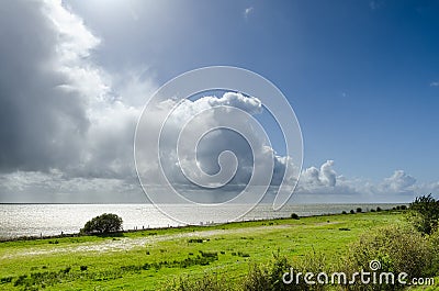 Tall cumulus clouds along the coast of lake IJsselmeer Stock Photo