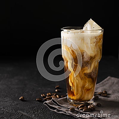 Tall glass cold brew coffee with ice and milk on black or dark b Stock Photo