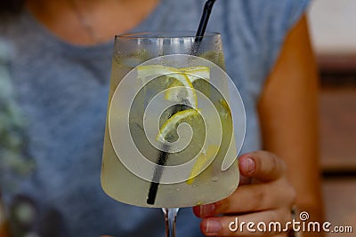 Tall glass of cold lemonade in woman`s hand on the table. Refreshment, drinks, beverag Stock Photo