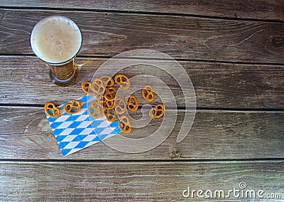 Tall glass of light beer with foam on a traditional napkin in a handful of pretzels with salt on a wooden table Stock Photo