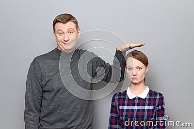 Tall man is showing height of short woman, people of different heights Stock Photo