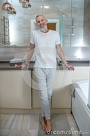 A tall mature amn standing in a bathroom and looking positive Stock Photo