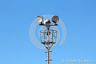 Tall metal pole with stairs leading to high; platform with three large electrical reflector lights Stock Photo