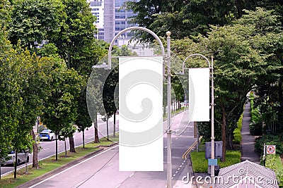 _Tall vertical hanging blank advertising banners posters mockup lush plants and tress in background for OOH out of home lamp post Stock Photo