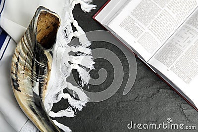 Tallit, shofar and open Torah on black table, flat lay. Rosh Hashanah celebration Stock Photo