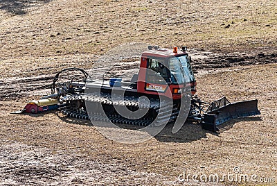 Talsi, Latvia - April 15, 2012: Red modern snowcat ratrack with snowplow snow grooming machine stay in spring day. Heavy machinery Editorial Stock Photo