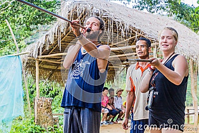 TAMAN NEGARA, MALAYSIA - MARCH 17, 2018: Tourists trying a blow pipe in an indigenous village in Taman Negara national Editorial Stock Photo