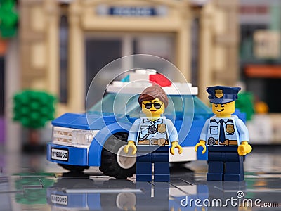Two Lego police officer minifigures standing in front of their police car Editorial Stock Photo