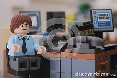 A Lego businessman minifigure sitting on a chair behind a computer in an office Editorial Stock Photo