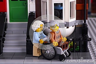 Lego senior couple near his house. Man siting in wheelchair, woman helping him Editorial Stock Photo