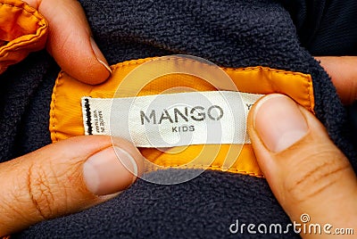 Woman holding yellow jacket with Mango Kids clothes label Editorial Stock Photo