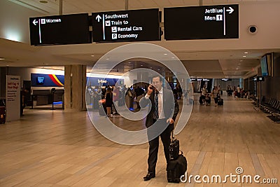 Businessman arrived from trip. He is walking with luggage. Editorial Stock Photo