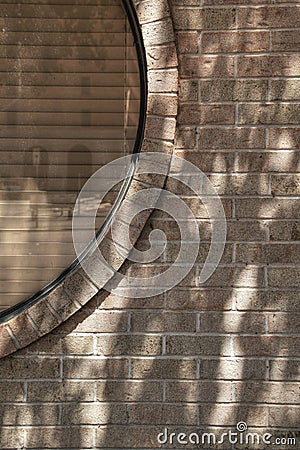 Tan brick wall with section of circular window covered by blinds Stock Photo