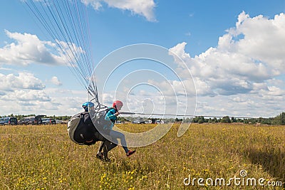 Tandem Paragliding takeoff from the field. Blue sky with clouds Editorial Stock Photo