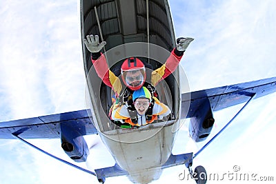 Tandem skydiving. Active woman are jumping out of a plane. Stock Photo