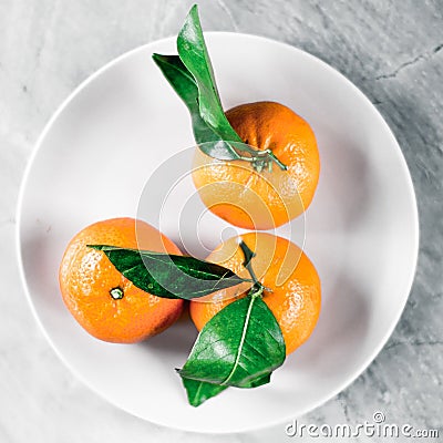 Tangerines with leaves on plate - citrus fruits and healthy eating flatlay concept Stock Photo