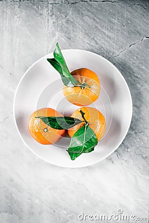 Tangerines with leaves on plate - citrus fruits and healthy eating flatlay concept Stock Photo