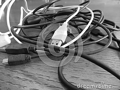 Tangle of dusty computer cables with sockets on the table . Black and white photo Stock Photo