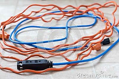 Tangled blue and orange extension cords on white background Stock Photo