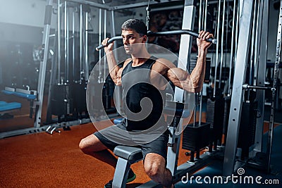 Tanned athlete workout on exercise machine in gym Stock Photo