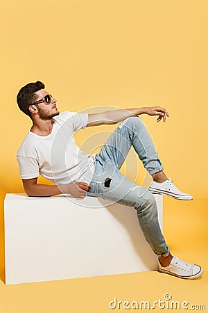 Tanned dude sitting on white box Stock Photo