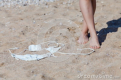 Tanned feet of woman and white bikini on sand Stock Photo