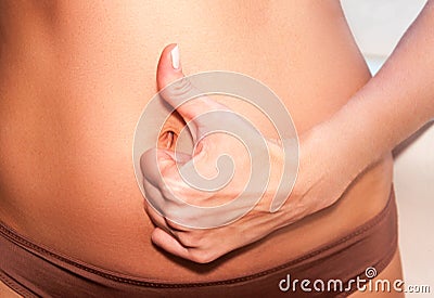 A tanned girl holds her hands to her stomach. IVF concept, pregnancy, digestion, health of the female reproductive system. Stock Photo