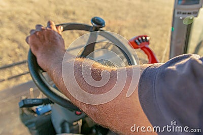 Tanned hand of the combine operator close-up on the steering wheel Stock Photo