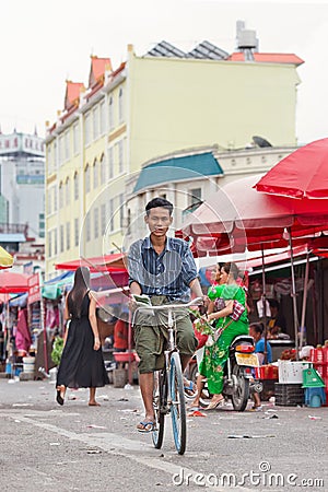 Tanned man cycles on a local outside market, Ruili, China Editorial Stock Photo