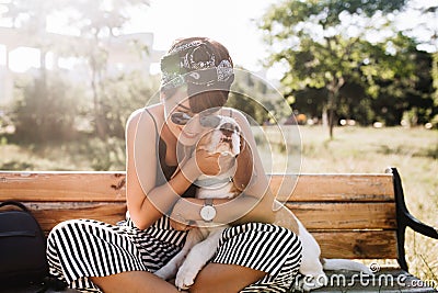 Tanned smiling lady in elegant wristwatch embracing beagle dog during rest in park in morning, Charming woman in Stock Photo