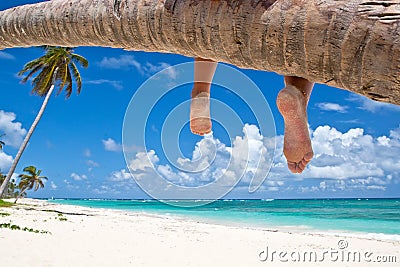 Tanned woman sitting on a palm white sand beach Stock Photo