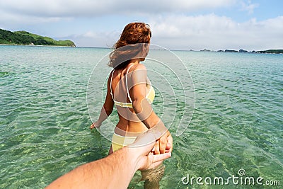 Tanned woman in swimsuit holding male hand follow me into sea water enjoying summer travel vacation Stock Photo