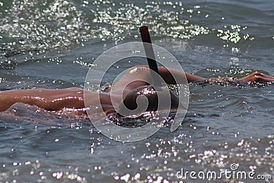 A tanned young male person diving with a black snorkel in the ocean Stock Photo