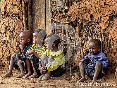 Group of Masai children are sitting near a traditional clay house. Editorial Stock Photo