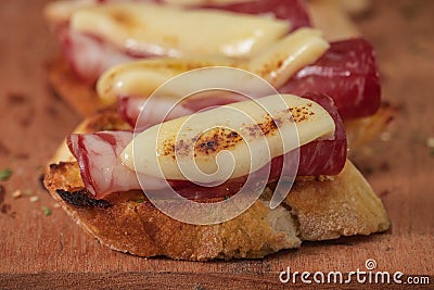 Tapas with Iberico ham, mozzarella cheese, roasted peppers on a slice of toasted baguette with olive oil Stock Photo