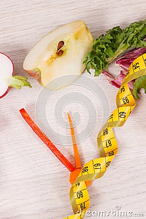 Tape measue with fruits and vegetables in shape of clock showing time to healthy eating and slimming Stock Photo