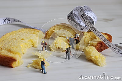 Tape measure and miniature workers on the bread. Stock Photo