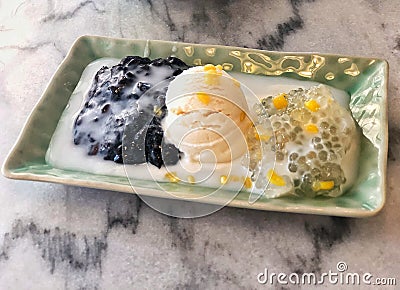 Tapioca pearl pudding with a dash of coconut milk, green sago coconut milk in green dish with yellow sweet corn and ice-cream. Stock Photo