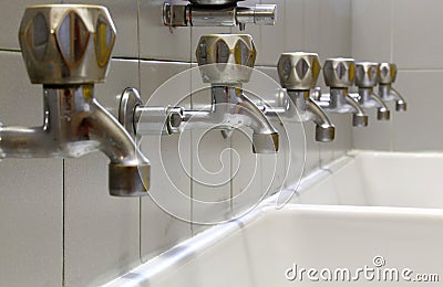 Taps lined up and a white ceramic washbasin Stock Photo