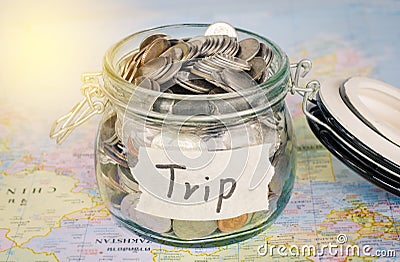 Target for travel - concept saving money in a glass and word `trip` on map. Stock Photo