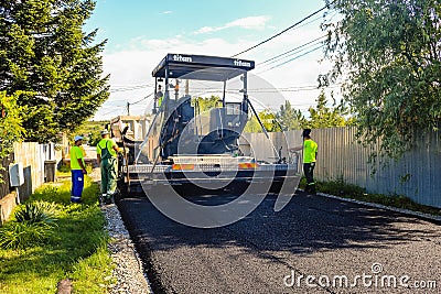 Targoviste, Romania - 2019. Close view on workers operating asphalt paver machine during road construction. Construction of a new Editorial Stock Photo